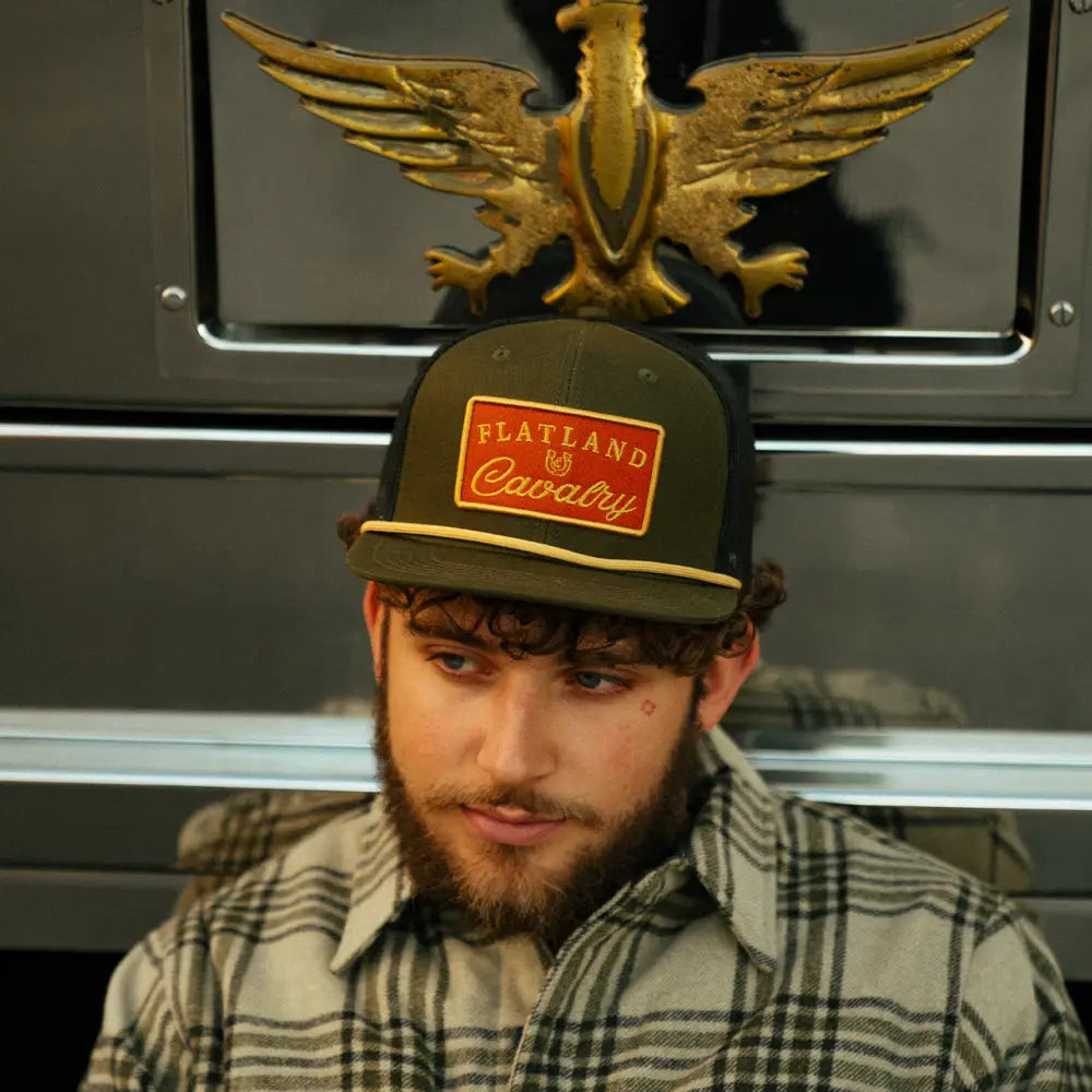 Hat with a golden eagle ornament on top and a ’Flatland Cavalry’ patch.