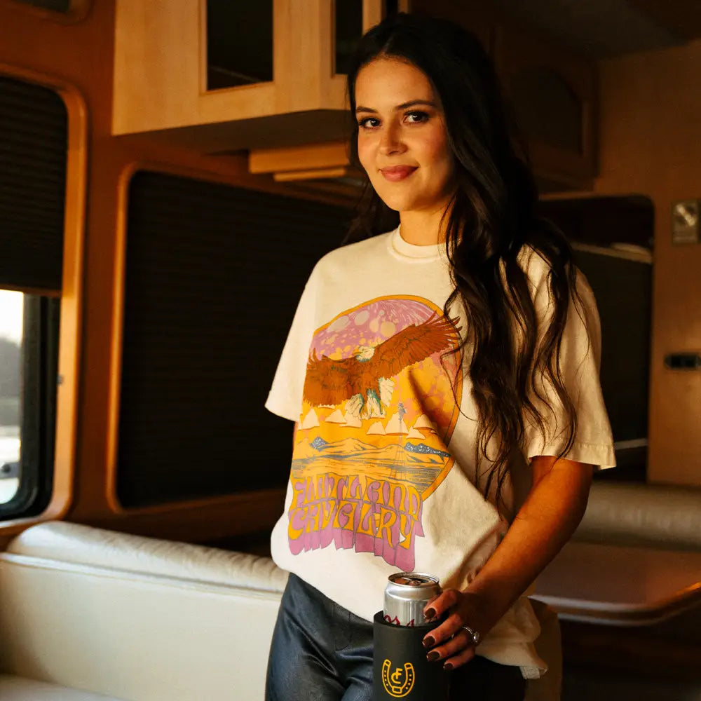 Woman wearing a white t-shirt with a colorful desert landscape design.