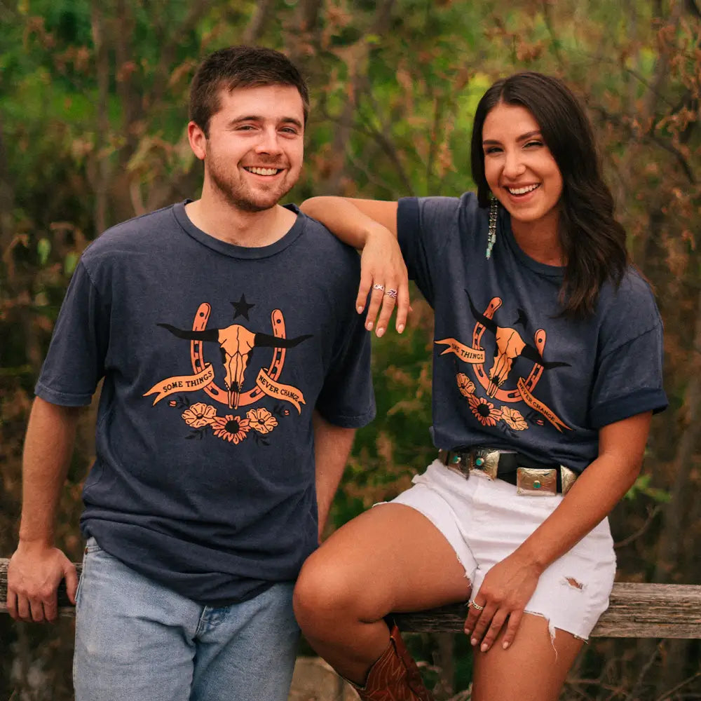 A smiling couple wearing matching navy t-shirts with orange designs.