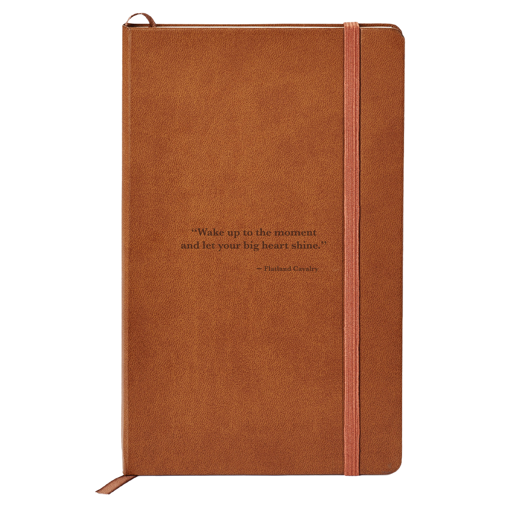 Brown leather-bound notebook with an elastic closure strap and an inspirational quote on the cover.